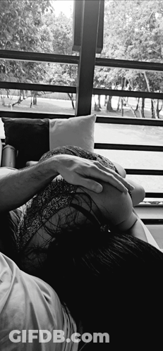 A Black And White Photo Of A Woman Laying On A Man 'S Lap GIF