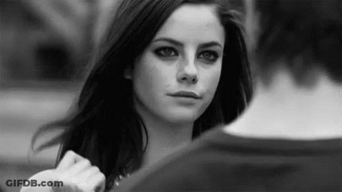 A Black And White Photo Of A Woman Looking At A Man In A Park . GIF