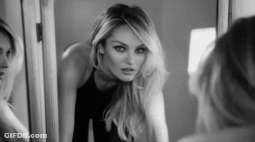 A Black And White Photo Of A Woman Looking At Her Reflection In A Mirror GIF
