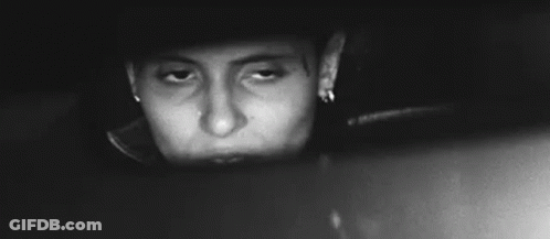 A Black And White Photo Of A Woman Looking At Herself In A Car Rear View Mirror . GIF