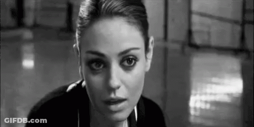 A Black And White Photo Of A Woman Looking At The Camera In A Room . GIF