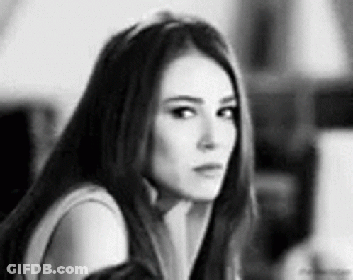 A Black And White Photo Of A Woman Looking At The Camera . GIF