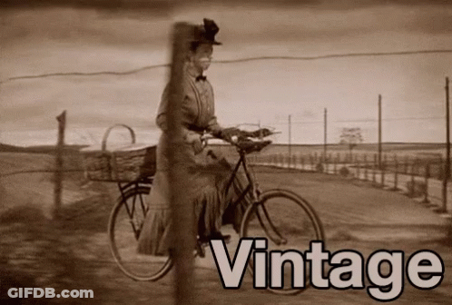 A Black And White Photo Of A Woman Riding A Bicycle With The Word Vintage Behind Her GIF