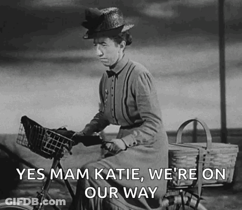 A Black And White Photo Of A Woman Riding A Bike With The Words Yes Mam Katie We 'Re On Our Way GIF