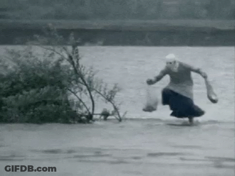 A Black And White Photo Of A Woman Running Through A Flooded Area . GIF