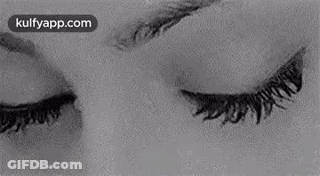 A Black And White Photo Of A Woman 'S Eyes Looking At The Camera . GIF