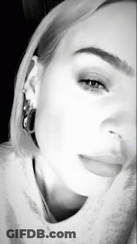 A Black And White Photo Of A Woman 'S Face With Hoop Earrings GIF