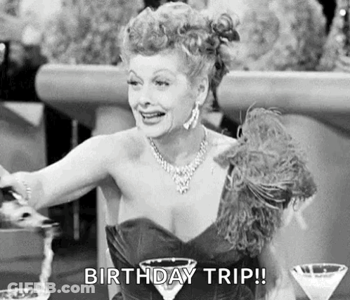 A Black And White Photo Of A Woman Sitting At A Table With A Martini Glass And A Birthday Trip ! GIF