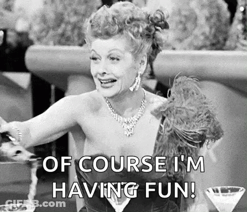 A Black And White Photo Of A Woman Sitting At A Table With A Martini Glass And A Feather Boa . GIF