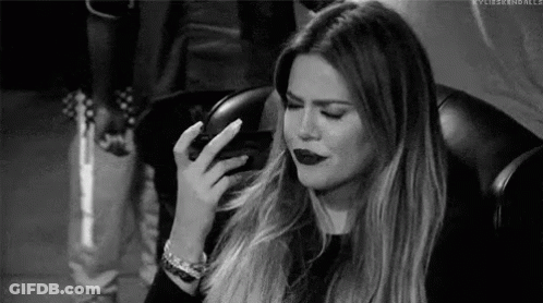 A Black And White Photo Of A Woman Sitting In A Chair With Her Hand On Her Face . GIF