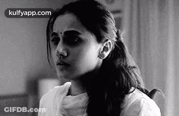 A Black And White Photo Of A Woman Sitting In A Chair With Her Hand On Her Neck . GIF