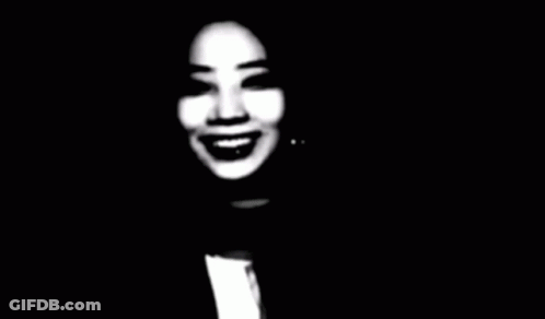 A Black And White Photo Of A Woman Smiling In The Dark GIF