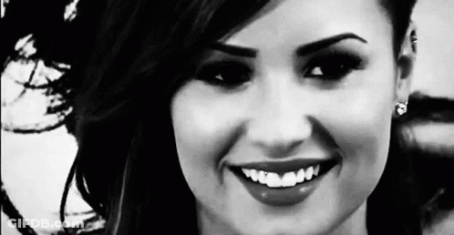 A Black And White Photo Of A Woman Smiling With Her Teeth Showing . GIF