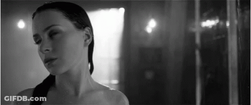 A Black And White Photo Of A Woman Standing In A Shower . GIF