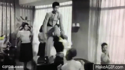 A Black And White Photo Of A Woman Standing On A Chair In A Living Room . GIF