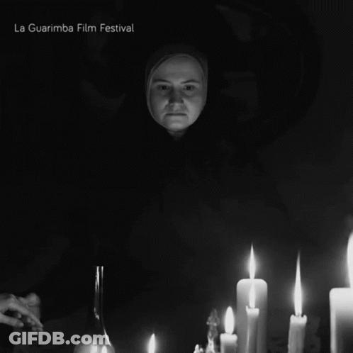 A Black And White Photo Of A Woman Surrounded By Lit Candles And The Words La Guarimba Film Festival Below Her GIF