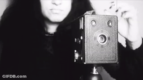 A Black And White Photo Of A Woman Taking A Picture With The Word She Visible GIF