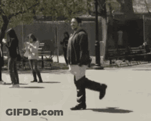 A Black And White Photo Of A Woman Walking Down A Street GIF