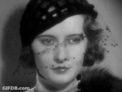 A Black And White Photo Of A Woman Wearing A Hat And A Veil GIF