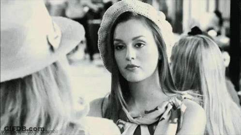 A Black And White Photo Of A Woman Wearing A Hat Talking To Another Woman . GIF