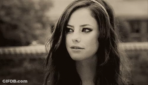A Black And White Photo Of A Woman Wearing A Headband And Looking At The Camera . GIF