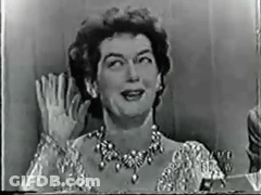 A Black And White Photo Of A Woman Wearing A Necklace Waving Her Hand . GIF