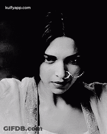 A Black And White Photo Of A Woman Wearing A Nose Ring And A Pearl Necklace . GIF