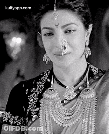 A Black And White Photo Of A Woman Wearing A Nose Ring And Earrings . GIF