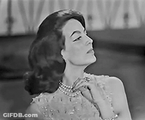 A Black And White Photo Of A Woman Wearing A Pearl Necklace And Bracelet . GIF