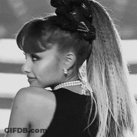 A Black And White Photo Of A Woman Wearing A Ponytail And Pearls GIF