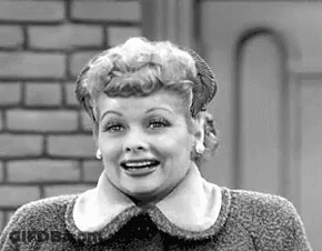 A Black And White Photo Of A Woman Wearing A Sweater And Smiling . GIF