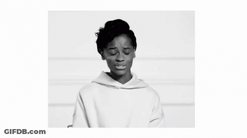 A Black And White Photo Of A Woman Wearing A White Hoodie And Looking At The Camera . GIF