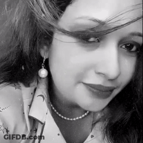 A Black And White Photo Of A Woman Wearing Pearl Earrings And A Pearl Necklace GIF