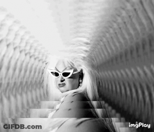 A Black And White Photo Of A Woman Wearing Sunglasses And A Wig GIF