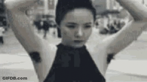 A Black And White Photo Of A Woman With A Bun On Her Head And A Bunch Of Hair On Her Armpits . GIF