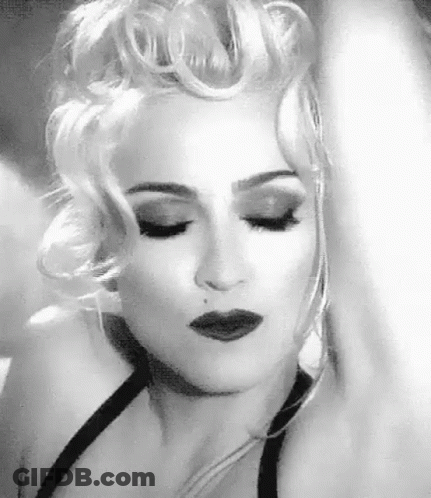 A Black And White Photo Of A Woman With Blonde Hair And A Black Dress . GIF