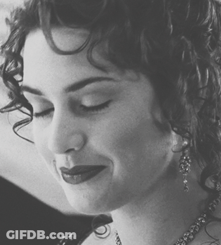 A Black And White Photo Of A Woman With Curly Hair And Earrings GIF