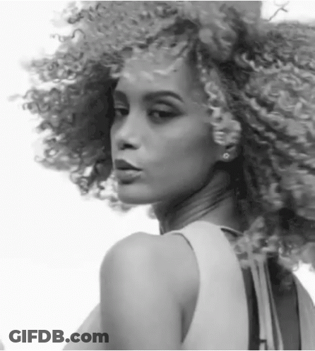 A Black And White Photo Of A Woman With Curly Hair And Earrings GIF