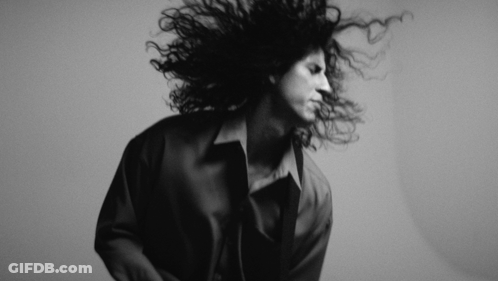 A Black And White Photo Of A Woman With Curly Hair GIF