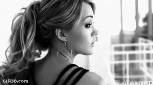 A Black And White Photo Of A Woman With Long Hair In A Ponytail . GIF