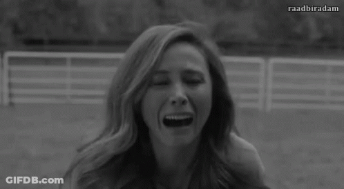 A Black And White Photo Of A Woman With Long Hair Sitting In A Field . GIF