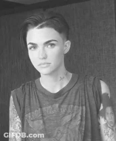 A Black And White Photo Of A Woman With Short Hair And A Tattoo On Her Neck GIF