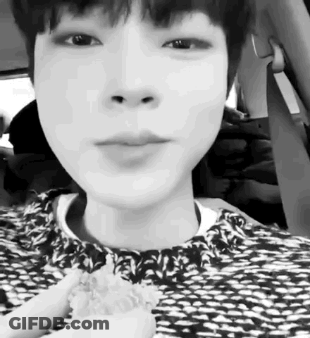 A Black And White Photo Of A Young Boy Sitting In A Car Eating A Sandwich . GIF