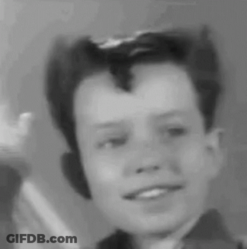 A Black And White Photo Of A Young Boy With A Mohawk Smiling . GIF