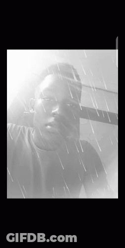 A Black And White Photo Of A Young Man In The Rain GIF