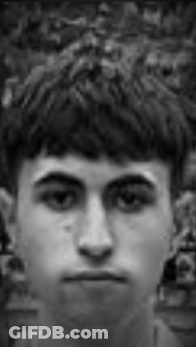 A Black And White Photo Of A Young Man Looking At The Camera . GIF