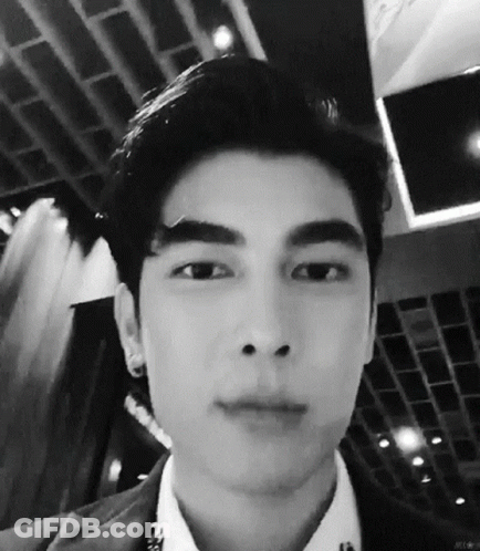 A Black And White Photo Of A Young Man 'S Face In A Suit And White Shirt . GIF