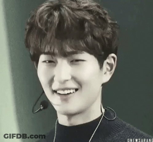A Black And White Photo Of A Young Man Smiling With A Microphone Around His Neck . GIF