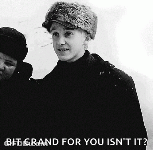 A Black And White Photo Of A Young Man Wearing A Fur Hat With The Caption Bit Grand For You Isn 'T It . GIF