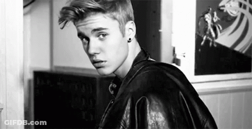 A Black And White Photo Of A Young Man Wearing A Leather Jacket And Earrings . GIF